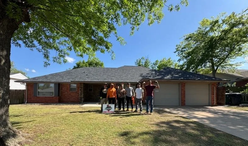 The Shoemaker Snoddy crew gathered in front of a finished roof with the company yard sign out front
