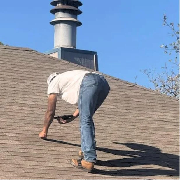 Crew member making a shingle repair near a roof turbine vent